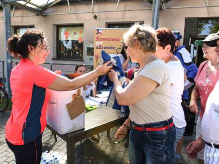 Zbiórka przed rajdem przy sali OSP w Bąkowie - Burmistrz Strumienia Anna Grygierek rozdaje uczestnikom kamizelki odblaskowe